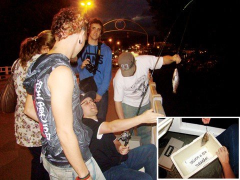 sera-que-da-peixe-1 Os futuros publicitários Cláudio Neto (sentado), André Wendhausen (segurando o peixe) e Eduardo Milioli (em pé, com a máquina fotográfica) mostraram muita criatividade e consciência ecológica ao protestar de maneira inusitada, em plena ponte Nereu Ramos.