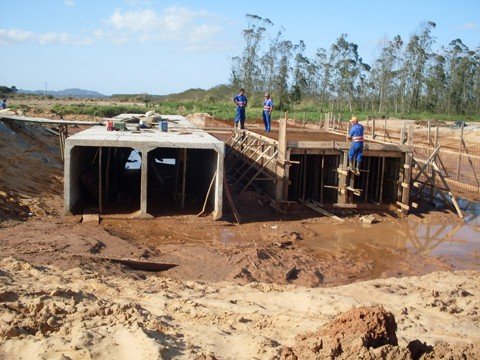 o-asfalto-chega-a-nova-estrada-1 Além da terraplenagem, existem frentes de trabalho na galeria de escoamento da água da chuva sobre o Rio Jaguaruna. Este é considerado o ponto mais crítico da obra, pois o solo é de baixíssima resistência e o local sofre com constantes alagamentos.