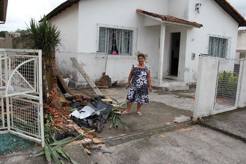 carro-pega-fogo-apos-colidir-em-muro-1 Dona Lindomar, de 67 anos, mostra o estrago em sua casa. Ela tomava café da manhã quando pulou da cadeira com o barulho da batida.