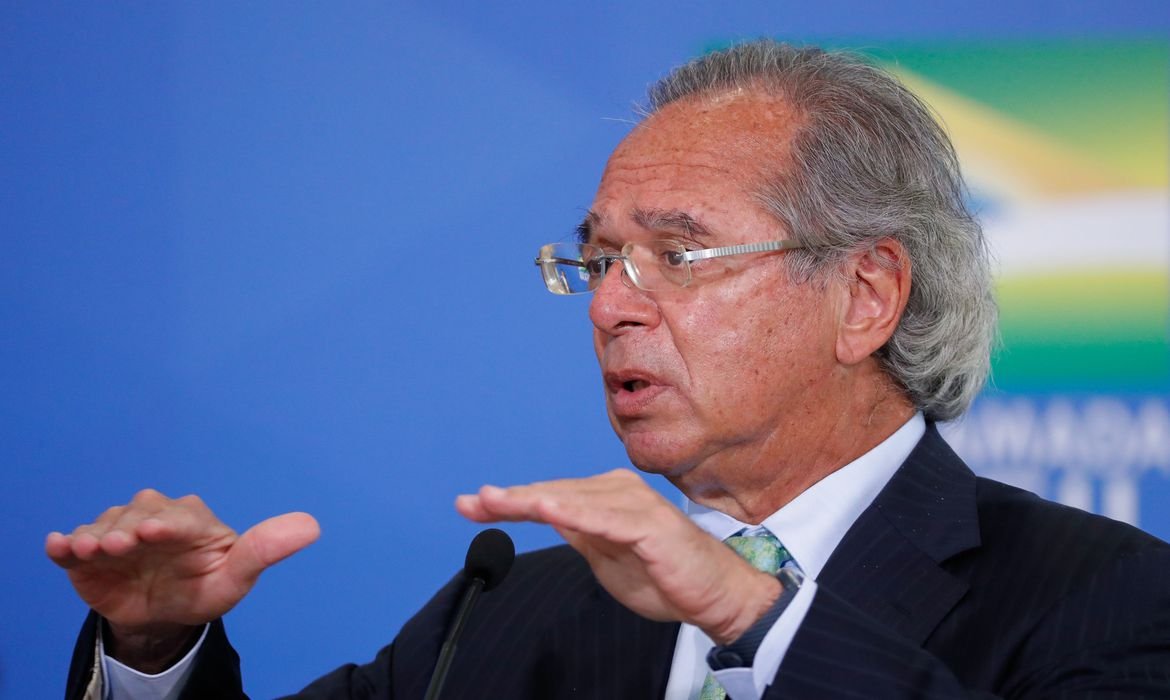 Guedes #Pracegover Foto: Na imagem há um homem, neste caso, o ministro da Economia Paulo Guedes, de terno e com os braços abertos