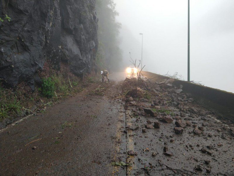 queda de barreira #Pracegover: Na imagem um policial aparece limpando a pista, que está com muito barro e terra