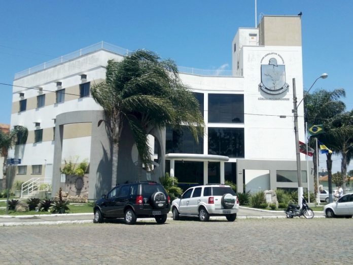casa-da-mae-joana-operacao-completa #Pracegover Foto: na imagem há um prédio, três carros, árvores e uma rua calçada
