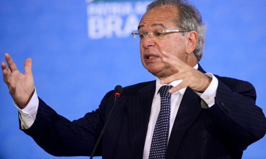 Guedes #Pracegover Foto: na imagem há um homem de terno, com cabelos grisalhos e de mãos abertas