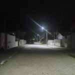 #Pracegover Foto: na imagem há um rua calçada, muros e postes com baixa iluminação