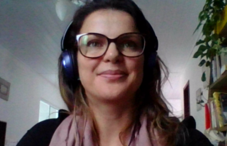 #Pracegover Foto: na imagem há uma muher de óculos e com fone de ouvido