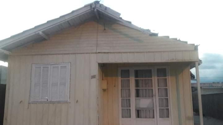 casa #Pracegover Foto: na imagem há uma casa de madeira na cor amarela e com janelas e portas brancas