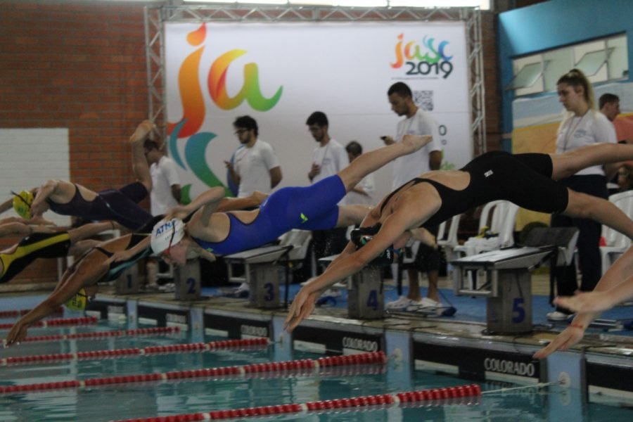 natação #Pracegover Foto: na imagem há várias pessoas e algumas delas se jogam na piscina