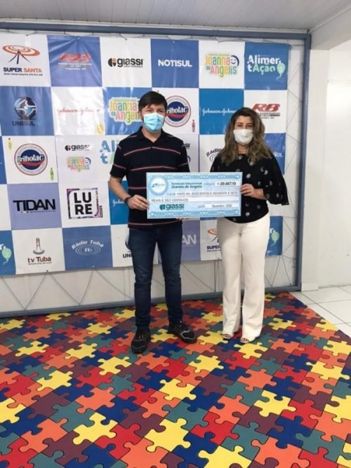 prestação #Pracegover Foto: na imagem há duas pessoas, um homem e uma mulher. Ambos seguram um cheque simbólico