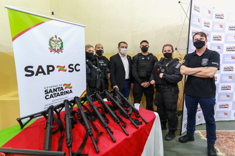Governador entrega equipamentos e veículos a agentes penitenciários de Tubarão #Pracegover Na foto, há uma mesa com fuzis e atrás pessoas sendo fotografadas