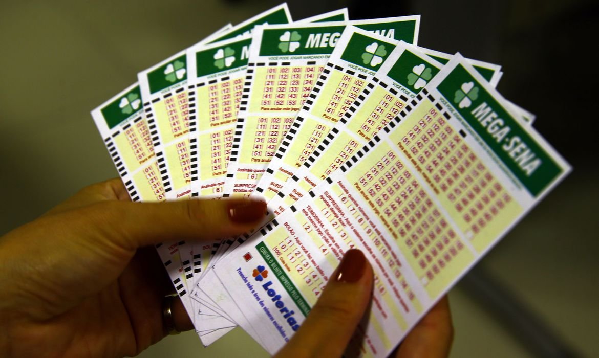 Mega-Sena sorteará nesta sábado prêmio de R$ 8 milhões #Pracegover Na foto, uma mulher segurando bilhetes de loteria