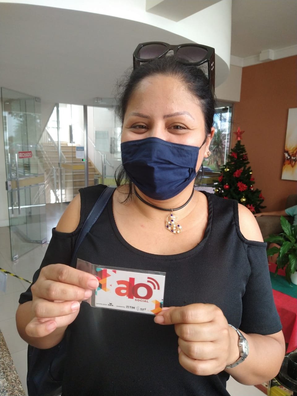 mulher #Pracegover Foto: na imagem há uma mulher de máscara segurando um chip telefônico