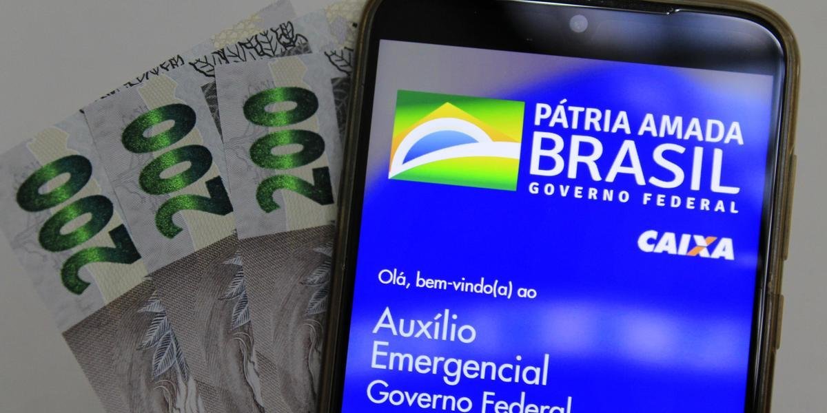 auxilio #Pracegover Foto: na imagem há um celular e cédulas de R$200