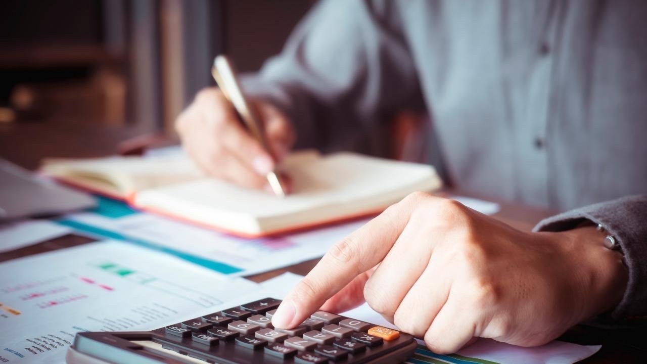 imposto q #Pracegover Foto: na imagem há uma pessoa fazendo contas e uma calculadora e escrevendo em um caderno