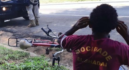jovem #Pracegover Foto: na imagem há duas pessoas, um veículo, uma bicicleta e uma rodovia