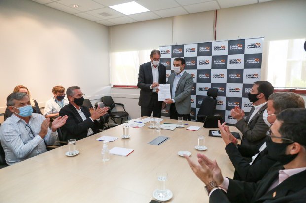 oximetros #Pracegover Foto: na imagem há várias pessoas reunidas, há uma mesa, celulares e folhas