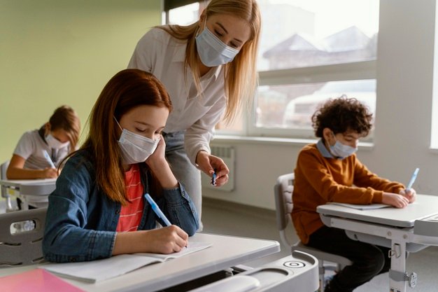 Prefeitura de Capivari de Baixo adia retorno das aulas após servidores testarem positivo para Covid-19 #pracegover Na foto, estudantes e uma professora usando máscara, dentro de sala aula mantendo distanciamento