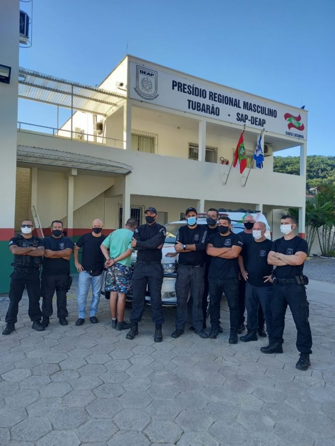 recapturado 1 #Pracegover Foto: na imagem há vários policiais penais, um detento e um edifício