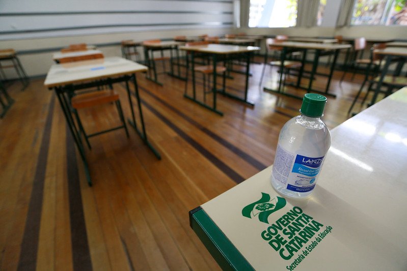 Sindicato dos professores de SC decide em assembleia suspender a greve no reinício das aulas #Pracegover Na foto, uma sala de aula com carteiras vazia, destaque para um frasco de álcool em gel sobre uma mesa.