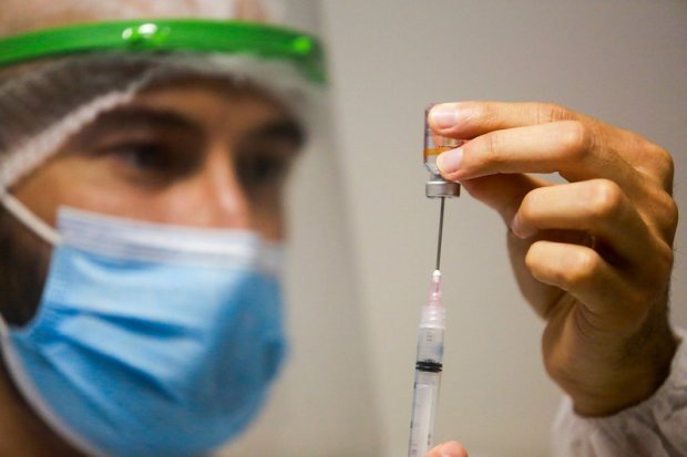 vacina covid #Pracegover Foto: na imagem há um homem de máscara, um frasco, seringa e agulha