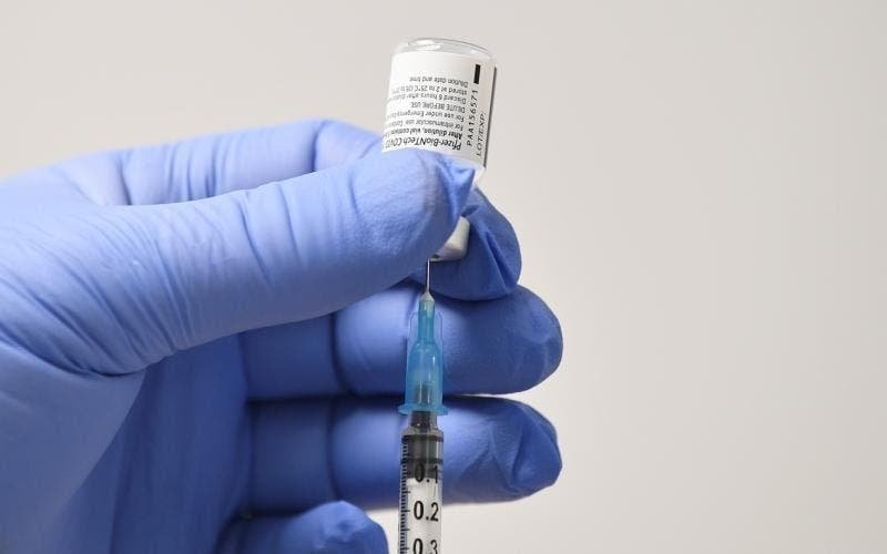 vacina #Pracegover Foto: na imagem há um frasco de vacina, uma seringa com agulha e uma mão com luva azul
