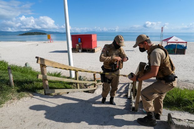 fiscalizacao na praia #Pracegover Foto: na imagem há dois homens, o mar, faixa de areia, barracas, calçada