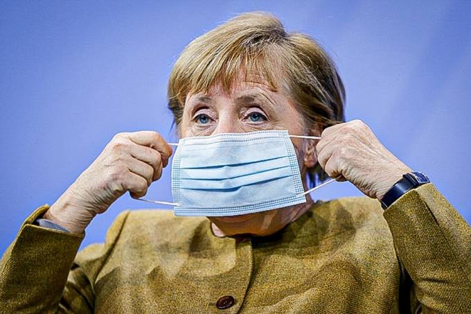 merkel #Praceover Foto: na imagem há uma mulher colocando a máscara
