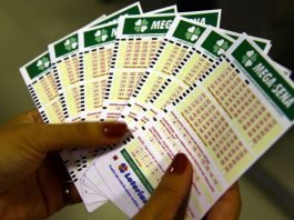 #pracegover Na foto, uma mulher segura vários bilhetes de loteria