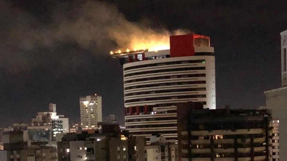 Vigilante inala fumaça tentando conter incêndio em edifício comercial de Criciúma #Pracegover Na foto, fumaça de incêndio sendo expelida pela cobertura do edifício
