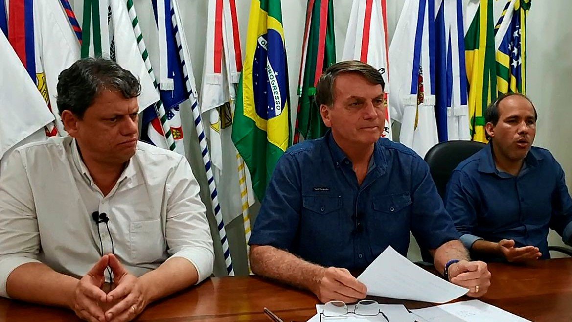 Bolsonaro negocia mudanças em projeto que muda ICMS sobre combustíveis #Pracegover Na foto, Bolsonaro está sentado em frente a uma mesa e acompanhado de outras duas pessoas
