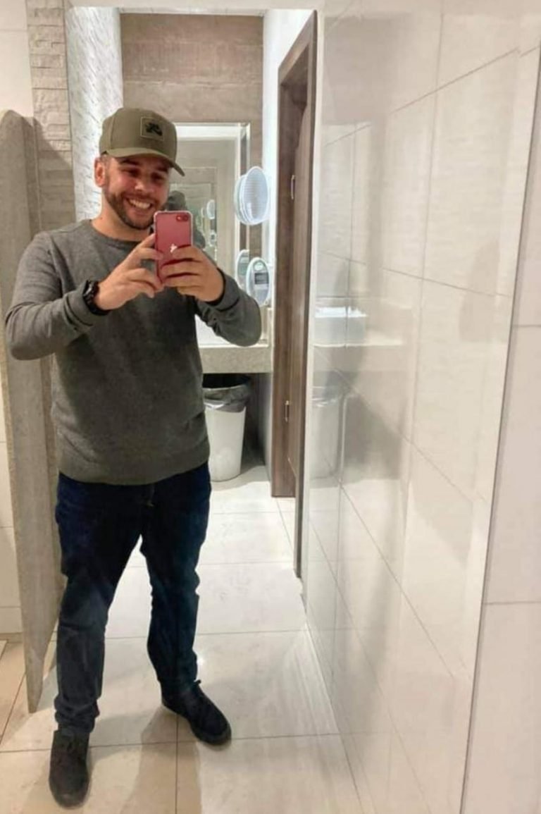 dédo #Pracegover Foto: na imagem há um homem de calça, blusa de lã, tênis, boné e segurando um celular