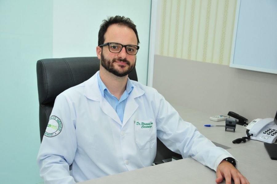 dr ricardo #Pracegover Foto: na imagem há um homem de óculos, uma mesa e cadeira