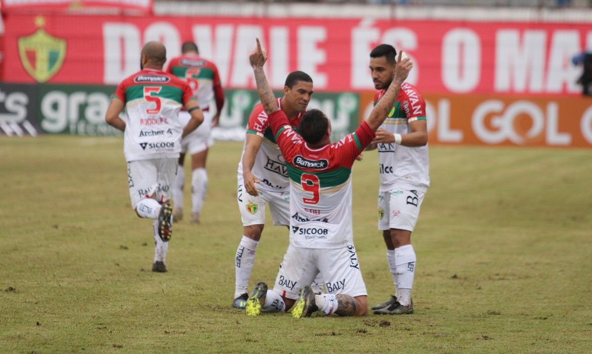 jogadores #Pracegover Foto: na imagem há alguns homens e um campo de futebol