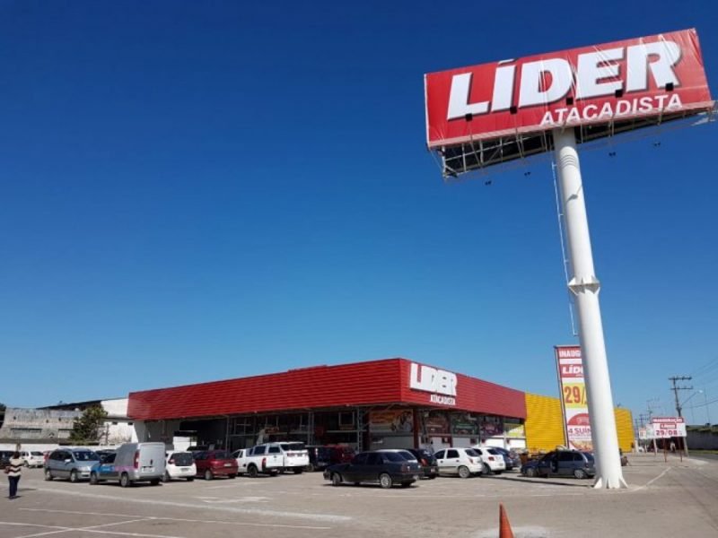 líder #Pracegover Foto: na imagem há uma placa, um estabelecimento comercial e carros