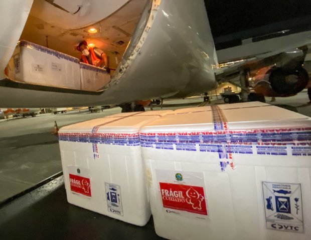 chegada das vacinas #Pracegover Foto: na imagem há uma aeronave e caixas