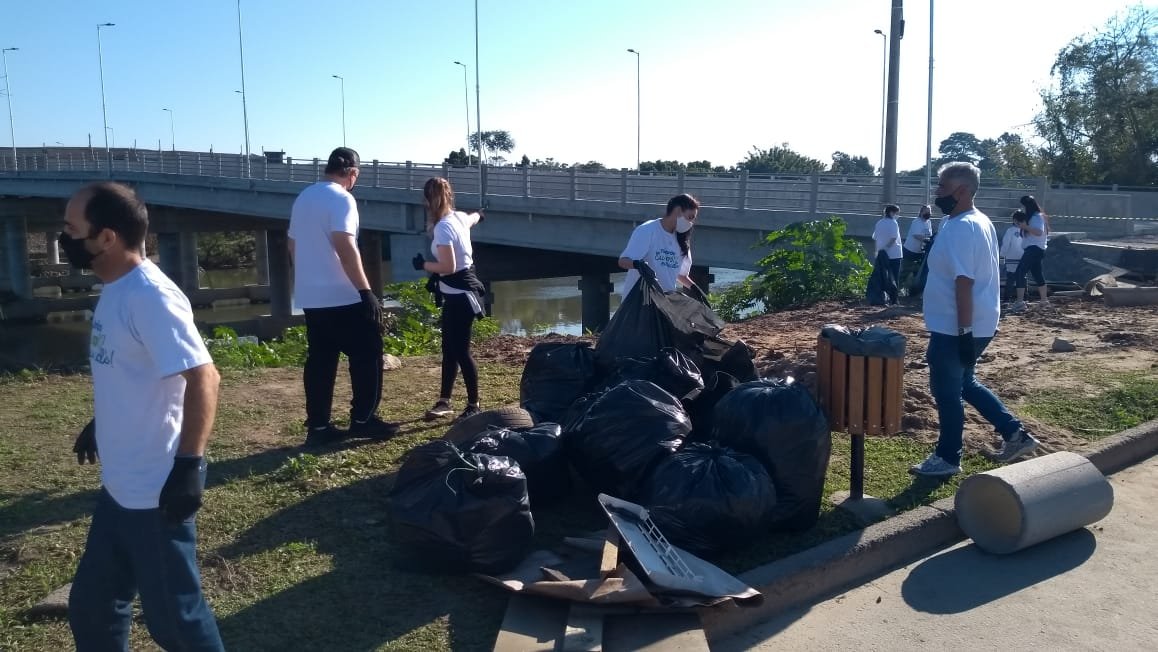 limpeza #Pracegover Foto: na imagem há pessoas, uma ponte, árvores e sacos de lixo
