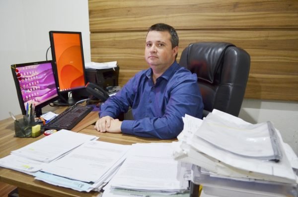 marivaldo #Pracegover Foto: na imagem há um homem, papéis, computador, cadeira e uma mesa
