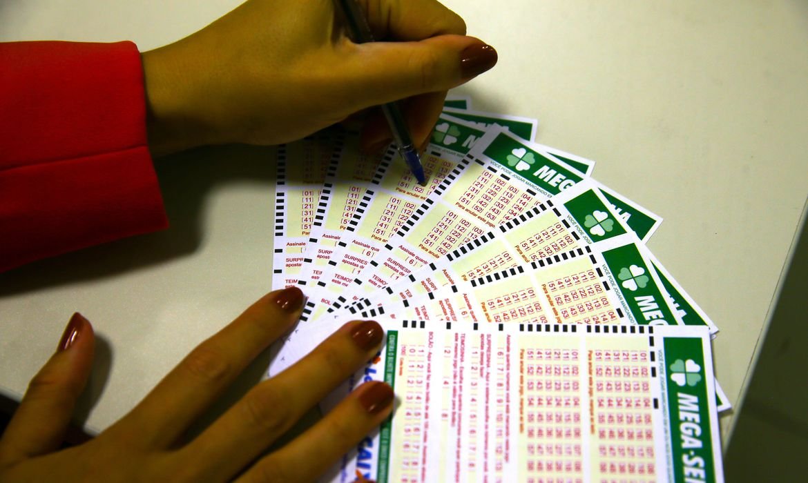 Mega-Sena acumula e próximo concurso deve pagar R$ 7,2 milhões #Pracegover Na foto, mulher marca números em bilhetes de loteria
