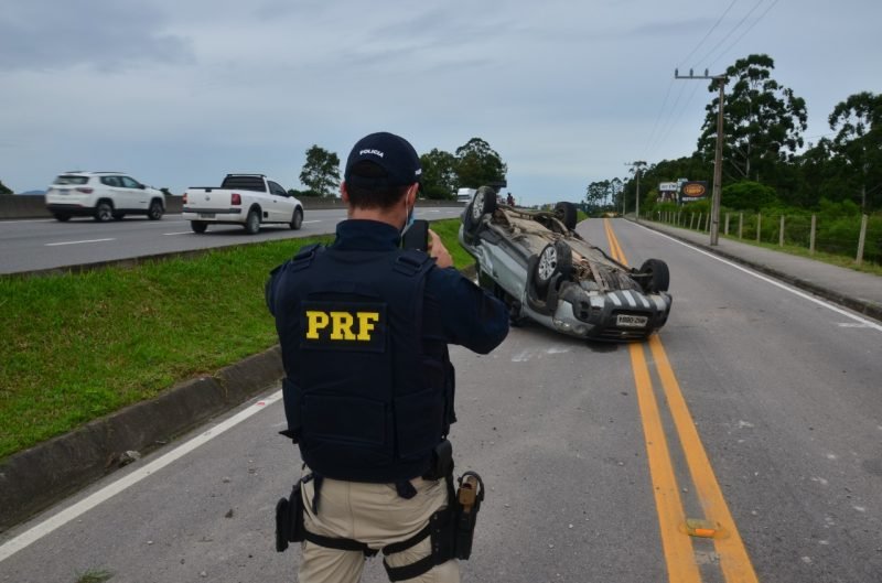 prf #Pracegover Foto: na imagem há um veículo virado, dois carros em uma via e um homem