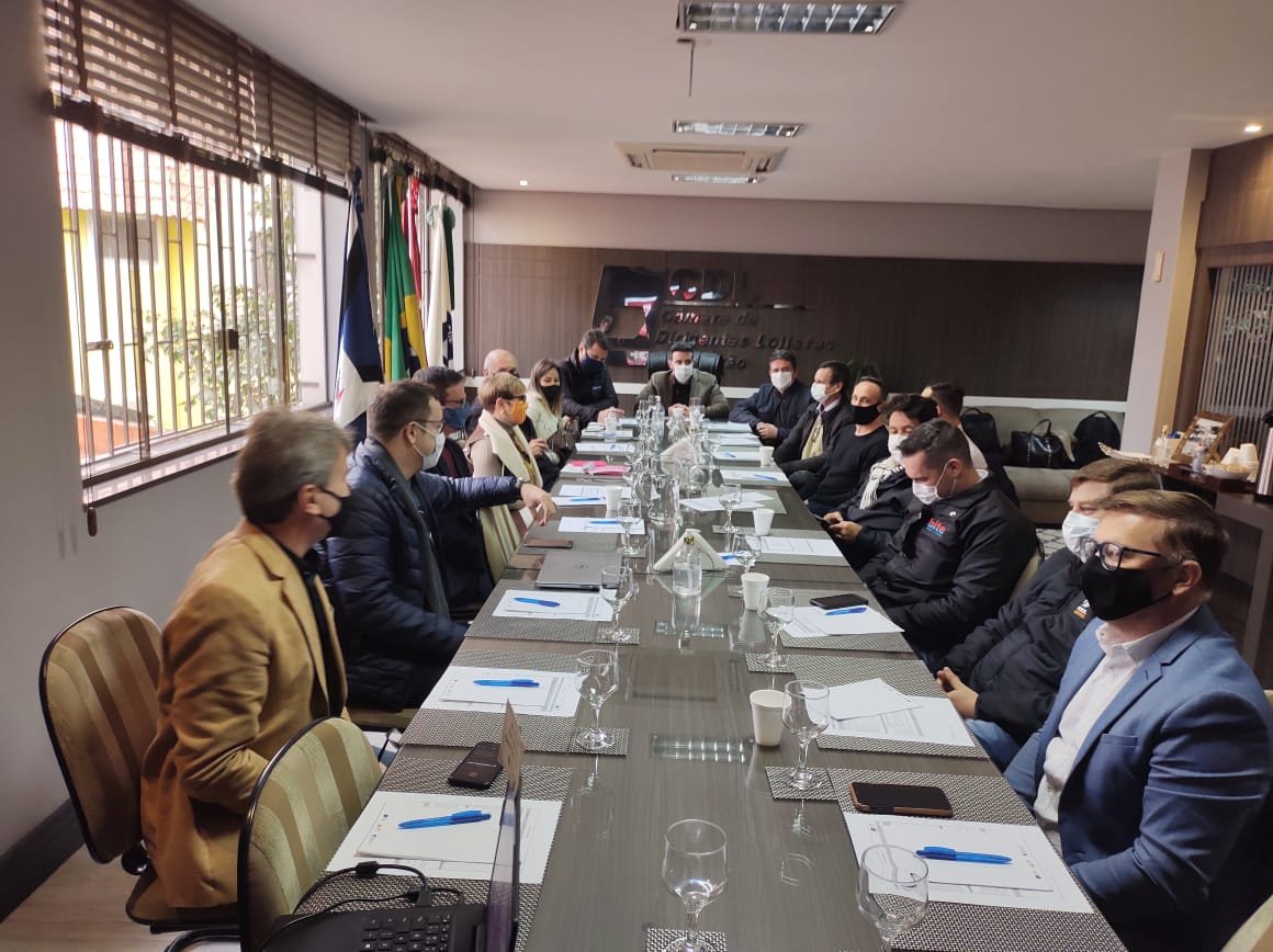 REUNIÃO CDL #Pracegover Foto: na imagem há pessoas, mesa, cadeiras, folhas, copos, canetas, bandeiras e celulares