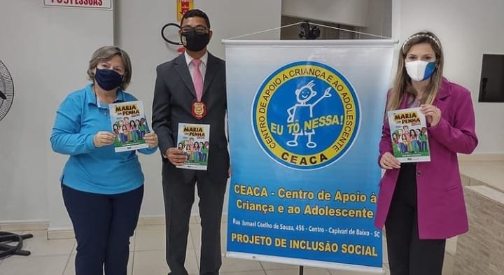 ceaca #Pracegover foto: na imagem há três pessoas e um cartaz