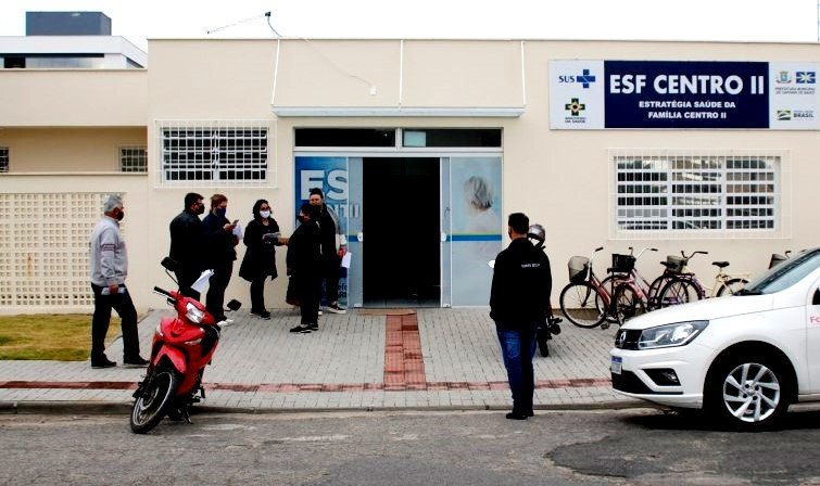 esf #Pracegover foto: na imagem há uma edificação, pessoas, moto, carro e bicicletas