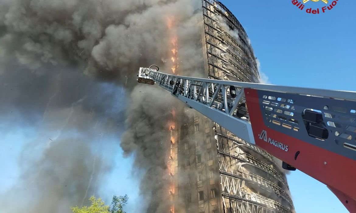 incendio em milão #Pracegover foto: na imagem há um prédio, fumaça e uma estrutura metálica