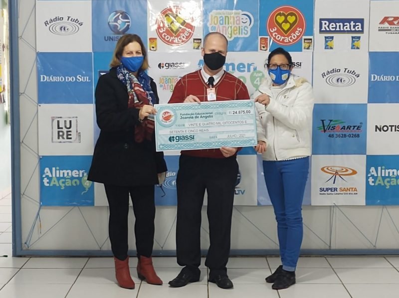 Joanna #Pracegover Foto: na imagem há três pessoas segurando um cheque simbólico