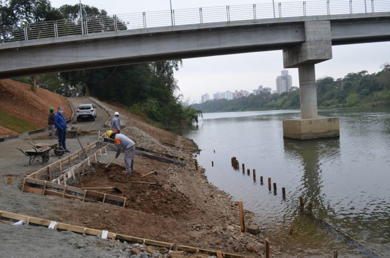 ponte #Pracegover Foto: na imagem há um rio, uma ponte, árvores e homens