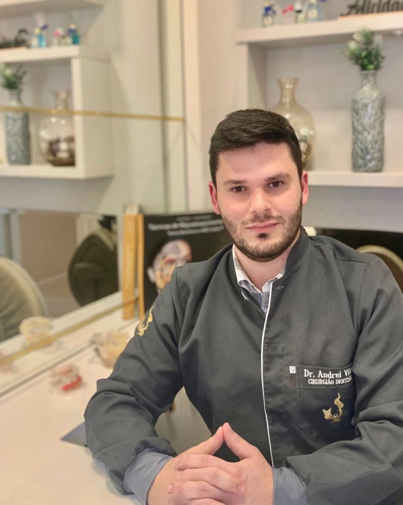 Andrei #Pracegover foto: na imagem há um homem de roupa cinza, uma mesa , um balcão e acessórios