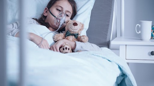 fibrose #Pracegover foto: na imagem há uma criança com um respirador, um urso de pelúcia e uma cama