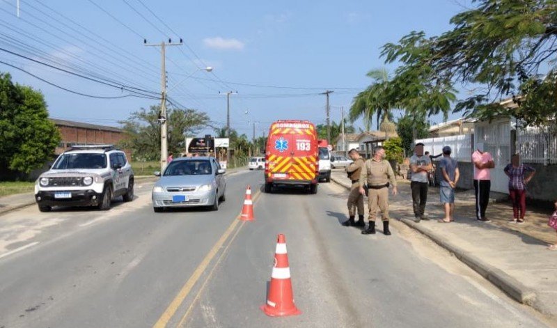 mf #Pracegover foto: na imagem há uma via, pessoas, carros, cones e árvores