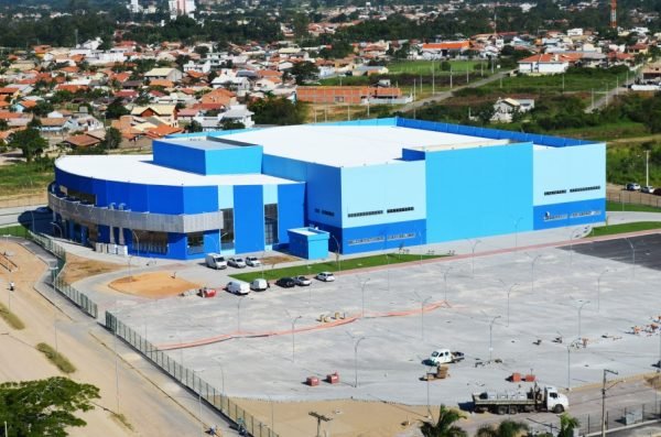 arena #Pracegover foto: na imagem há construções, árvores e veículos