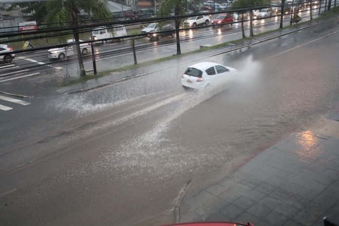 Defesa-Civil-alerta-para-chuvas-intensas-em-SC-no-fim-de-semana #Pracegover foto: na imagem há carros, chuva, vias e árvores