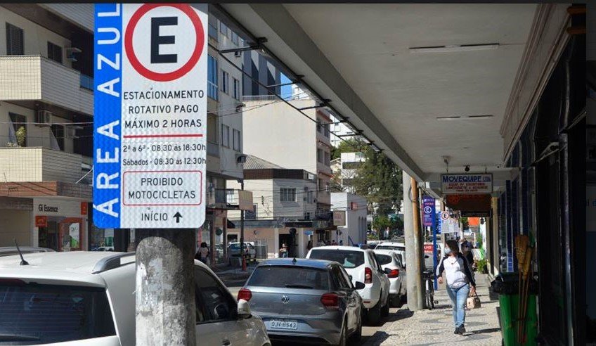 Prefeitura de Tubarão lança nesta sexta-feira licitação para operação do sistema de estacionamento rotativo #Pracegover foto: na imagem há veículos, via, edificações, postes, placa e pessoas